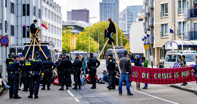 Demonstranten en politie met spandoek: Crisis is nu