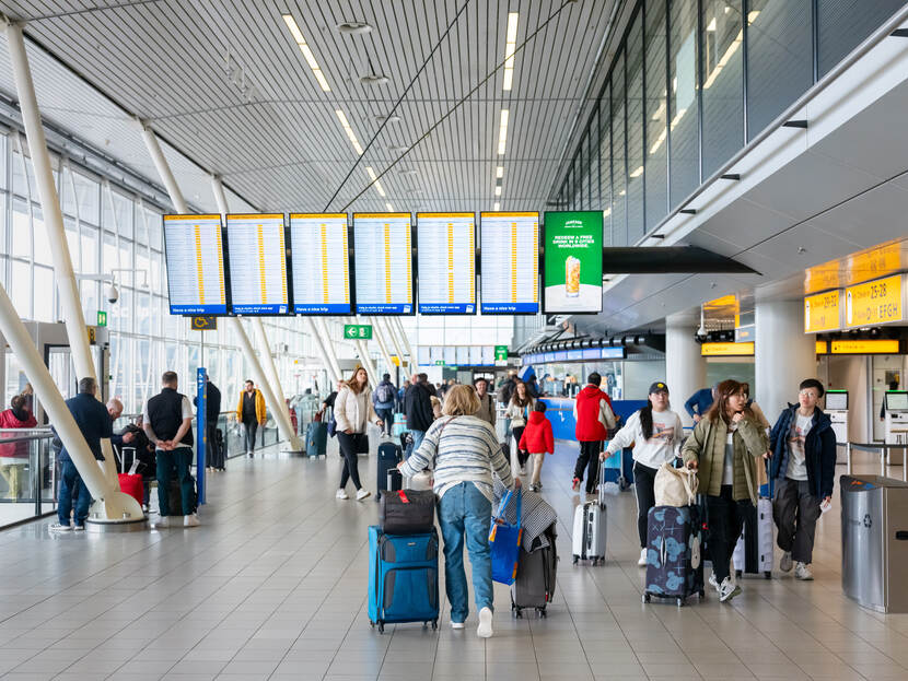 Mensen met koffers in de vertrekhal op Schiphol