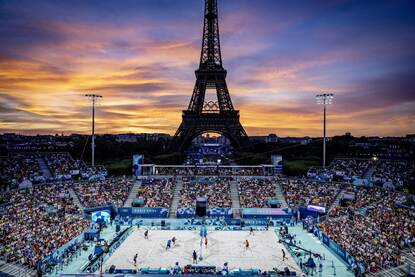 Het beachvolleybalstadion in Parijs tijdens de Olympische Spelen, met op de achtergrond de Eifeltoren, terwijl de zon net onder gaat