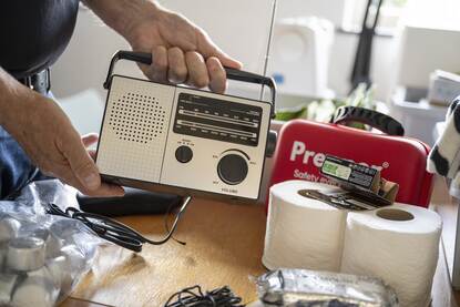 Iemand stelt een noodpakket samen, met onder meer een noodradio en wc-rollen